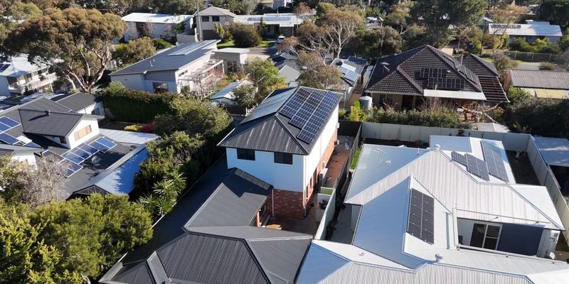 Aerial view over the street to the finished second storey, its solar roof rising above the neighbouring rooftops