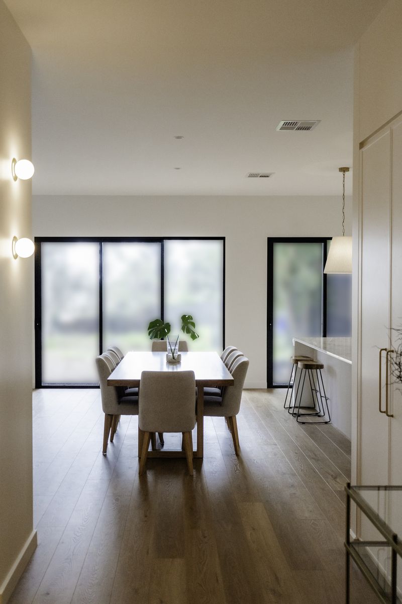 Hallway with oak floors leading through to the dining area and black-framed sliders