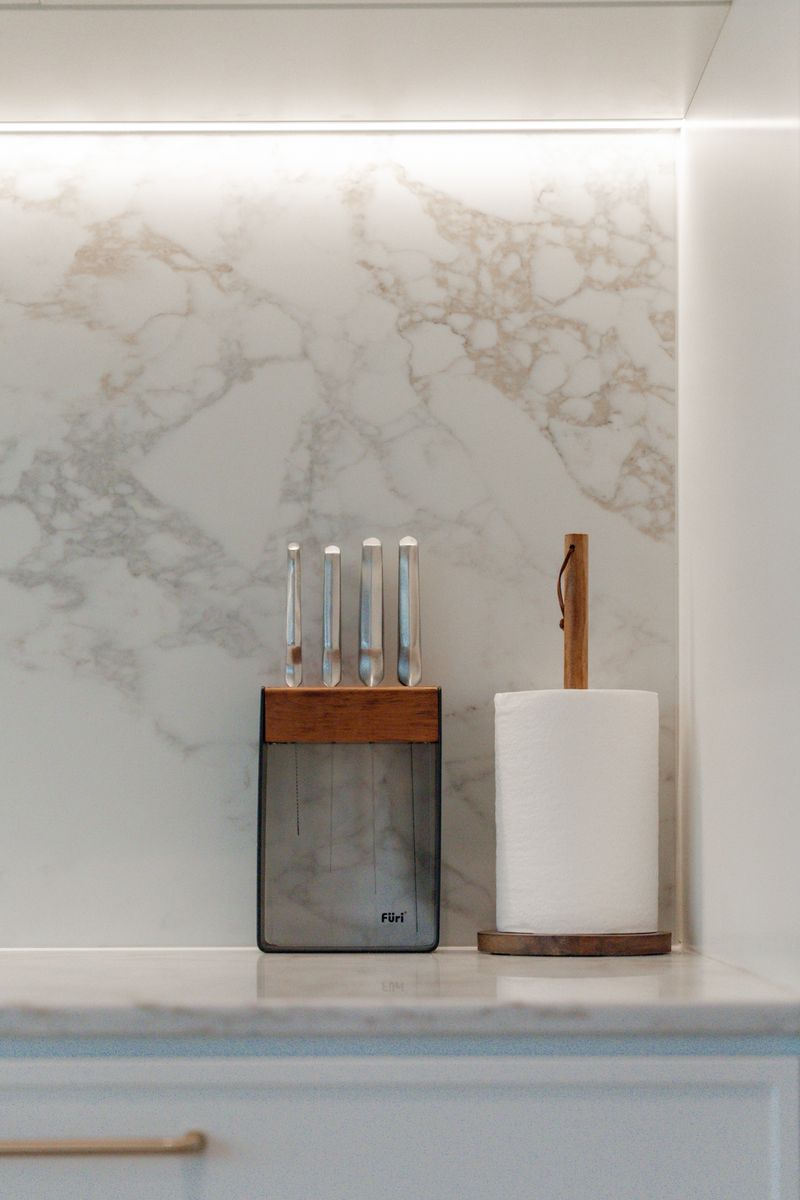 Close-up of the Eleganto Gold stone splashback with LED strip lighting above the bench