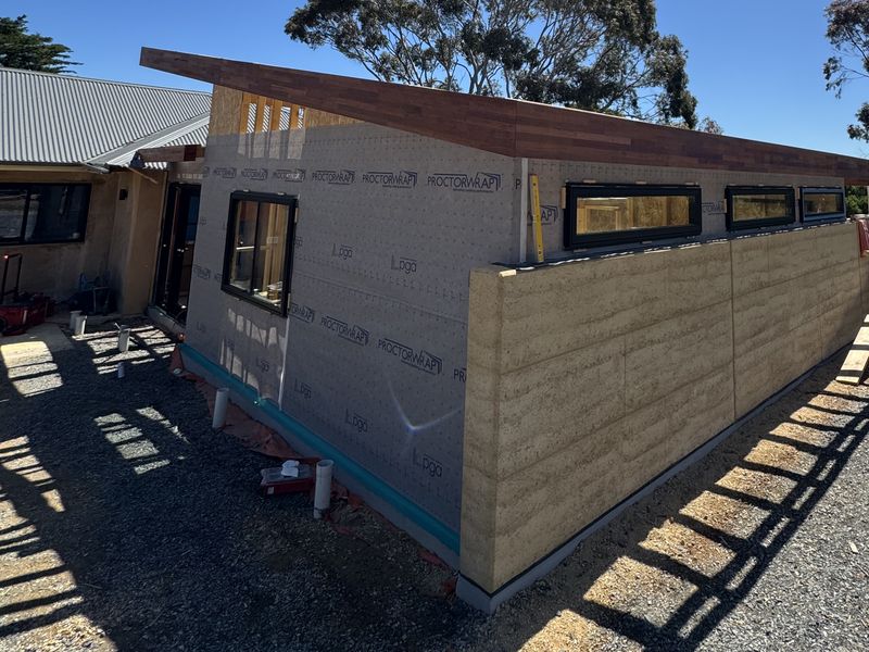 The Willunga addition: a long rammed-earth wall beneath a timber-edged skillion roof with highlight windows